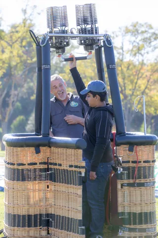 Crew stand at the burners above a balloon basket