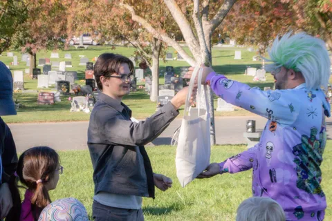 Two people hand over a tote bag on the lawn