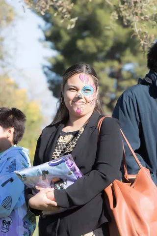 A guest with face paint carries a bag at the festival