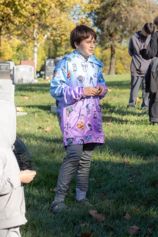 A child in a bright jacket stands on the grass