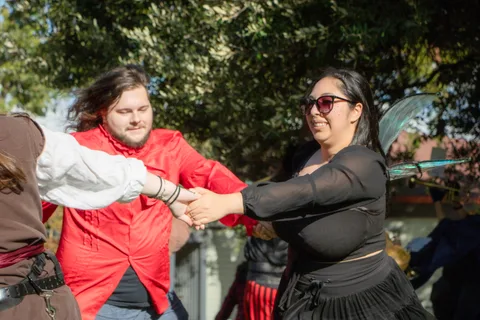 Two band members clasp hands and dance together in the sunshine.