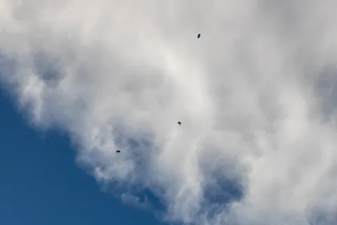 Two skydivers fall away from the cloud line high above the park.