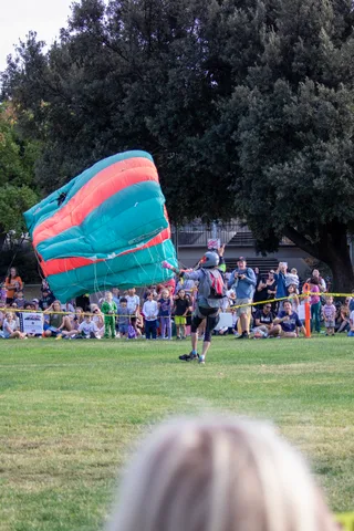 A skydiver walks the field as the canopy collapses behind.