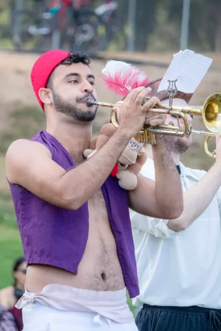 A trumpeter in a purple vest plays beside a bandmate in white.