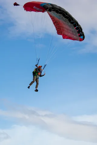 A red canopy glides across a clear patch of blue sky.