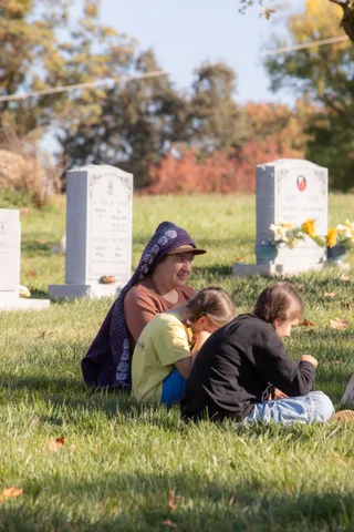 A family sits together on the grass in the morning sun