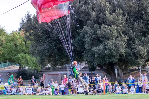 A pink canopy passes low over the spectators at the ropes.