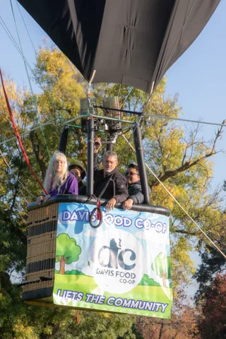 Passengers ride in a balloon basket above the treetops