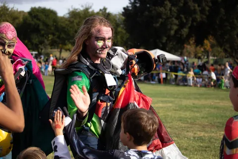 Two skydivers in face paint wave to guests along the field.