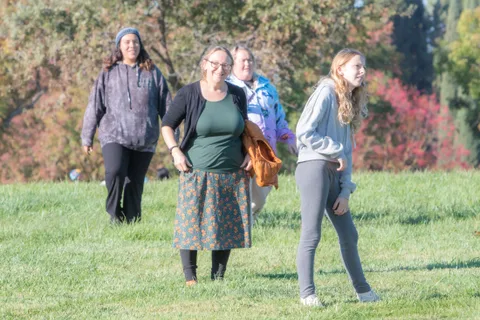 People walk across the grass with trees behind them