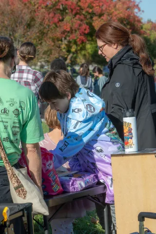 People browse merchandise at a table under the trees