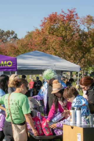 People crowd around a merchandise table under a canopy