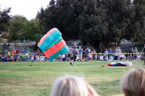 A canopy lies on the grass with another bundled nearby.