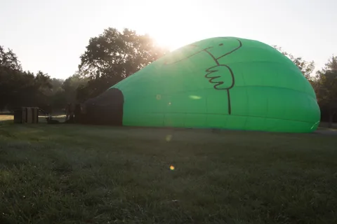 A green balloon glows against the low morning sun