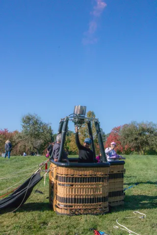 A balloon basket waits on the grass with the envelope laid out.