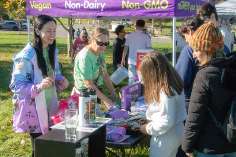 Volunteers and guests around a merchandise table under a tent