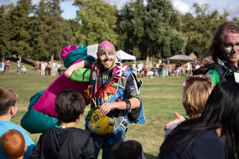 Two skydivers in face paint stop to greet the children.