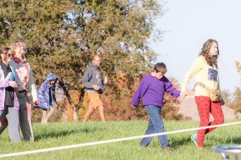 People walk across the grass past a rope line