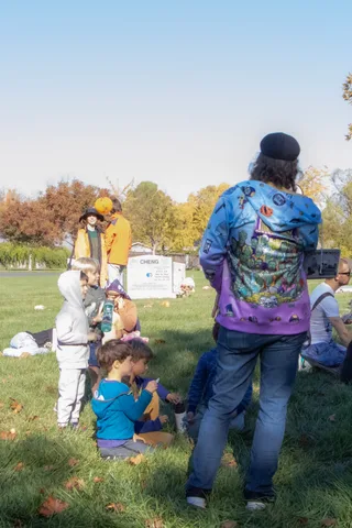 People gather on the grass near a booth