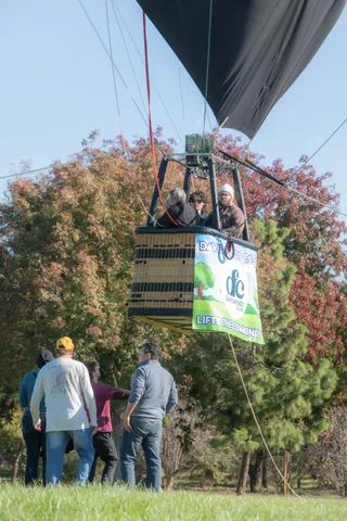 A basket with a sponsor banner drifts low above the trees
