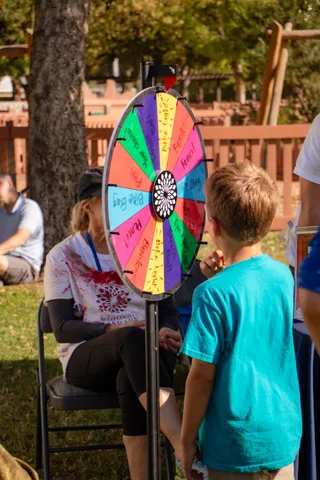 A child spins a coloured prize wheel at a game booth.