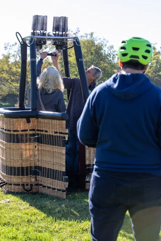 People stand around a balloon basket on the lawn