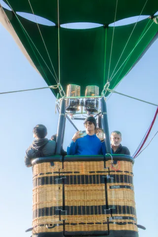 Passengers stand in a balloon basket seen from below
