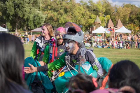 A skydiver in face paint spreads both arms while walking in.
