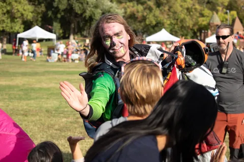 A skydiver in face paint high fives a child at the crowd line.