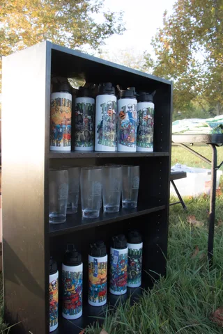Water bottles and glasses on a shelf at the merchandise stand