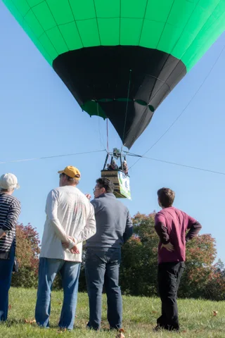 A family watches a green balloon passing overhead