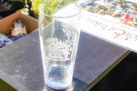 An etched commemorative pint glass on a table in the sun