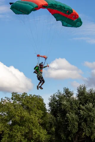 A green and orange canopy floats over the trees in a blue sky.