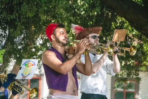 Two trumpeters play side by side, one of them in a pirate hat.