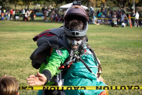 A skydiver reaches across the tape to greet a young fan.