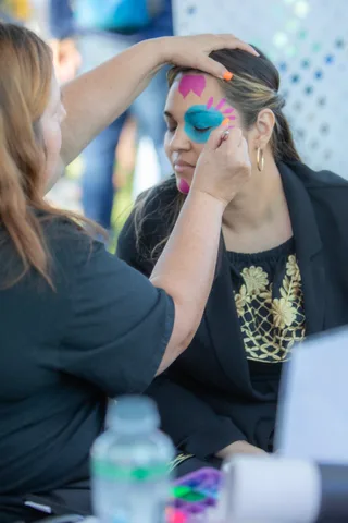 Face paint being applied to a smiling guest at the painting booth