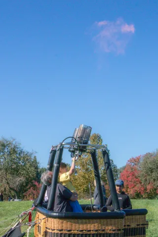Crew stand in a balloon basket under a clear blue sky