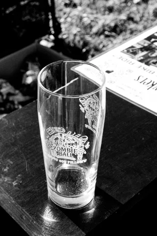 A black and white photo of an etched pint glass on a table