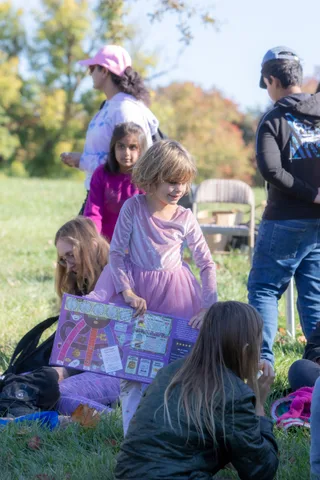 Children sit together on the grass with a poster
