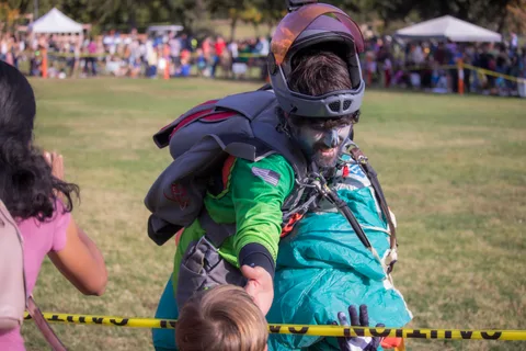A young guest reaches out to high five a skydiver in face paint.