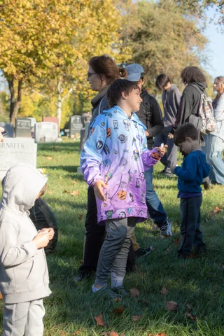 A family walks across the grass past a row of headstones