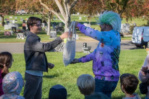 A person in costume hands a bag to a guest