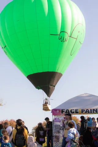 A green balloon rises above the face painting tent