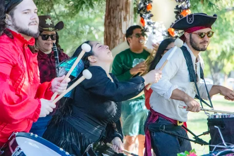 The costumed brass band plays, a mallet player arching back in the middle of the line.
