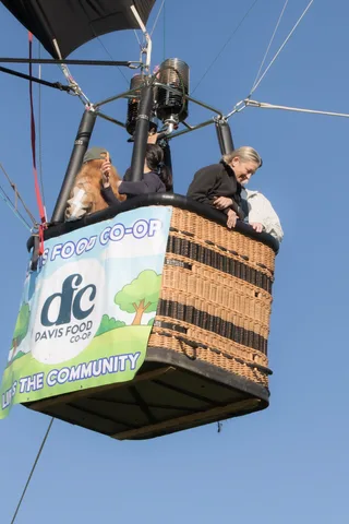 Passengers look down from a sponsored balloon basket