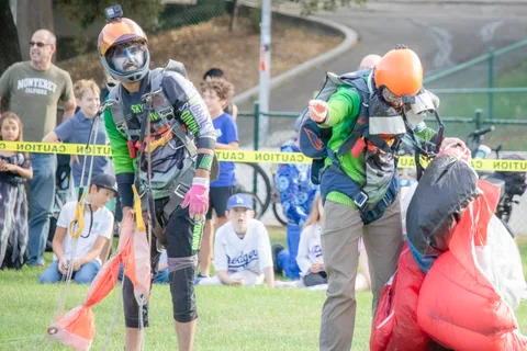 Two skydivers carry their gear past the watching spectators.