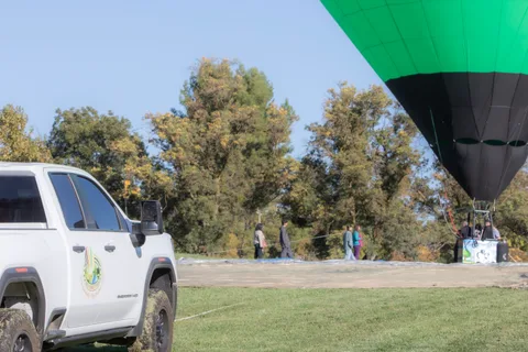A pickup truck parked as a balloon settles in the background
