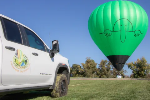 A green balloon rises beyond a parked truck