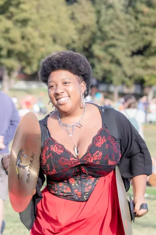A cymbal player walks the field mid performance, cymbals at her side.