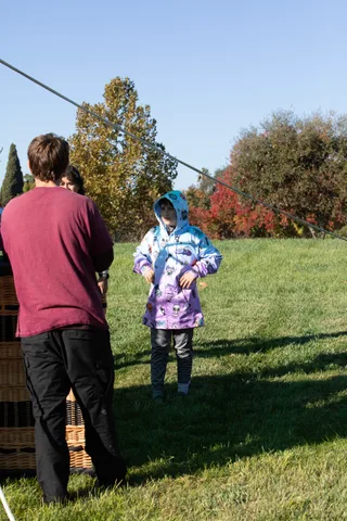 A family stands watching beside a balloon basket